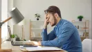 Unavený podnikateľ s hlavou v dlani pri notebooku rieši sankcie za švarcsystém