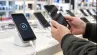 mobilné telefóny v predajni elektroniky, na displeji ikona aktualizácie, zákazník drží telefón