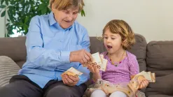 Staršia žena s malou vnučkou držia v rukách eurobankovky