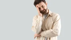muž s rukou na tvári na sivom pozadí, štúdiový záber