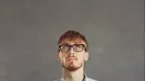 Mladý muž s okuliarmi zamyslene hľadí nahor
