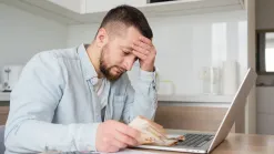 Mladší muž s peniazmi v ruke sa ustarostene pozerá pred seba