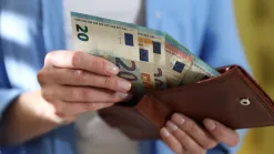 Ruky vyberajú dvadsaťeurové bankovky z kožnej peňaženky