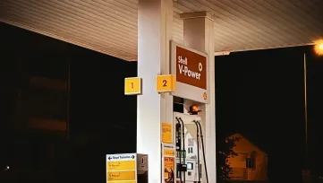osvetlený výdajný stojan čerpacej stanice v noci, tankovacie pištole a cenový panel