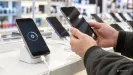 mobilné telefóny v predajni elektroniky, na displeji ikona aktualizácie, zákazník drží telefón