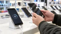mobilné telefóny v predajni elektroniky, na displeji ikona aktualizácie, zákazník drží telefón