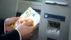 ruky držia eurobankovky pri bankomate