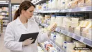Inšpektorka kontroluje balené potraviny v regáli supermarketu